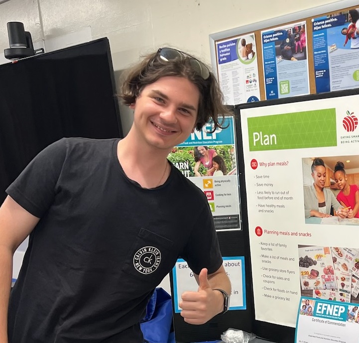 Vlad gives a thumbs up at an event with lesson poster