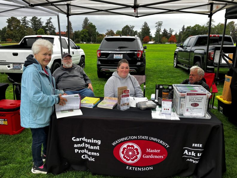 Four volunteers sitting behind farmer's market table.