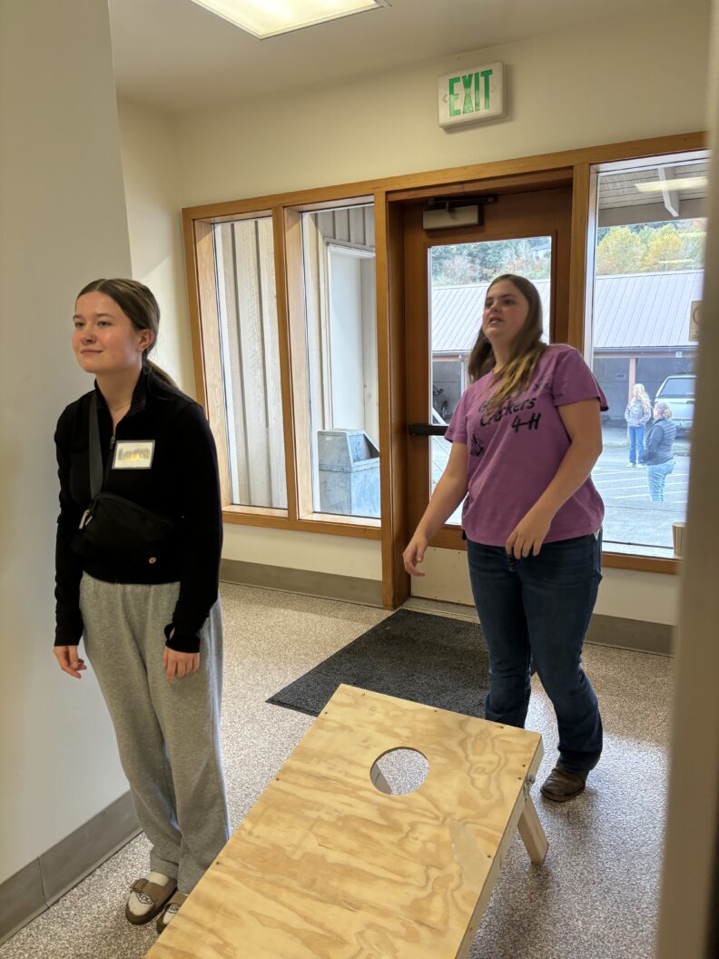 Youth playing the cornhole game at teen rally.
