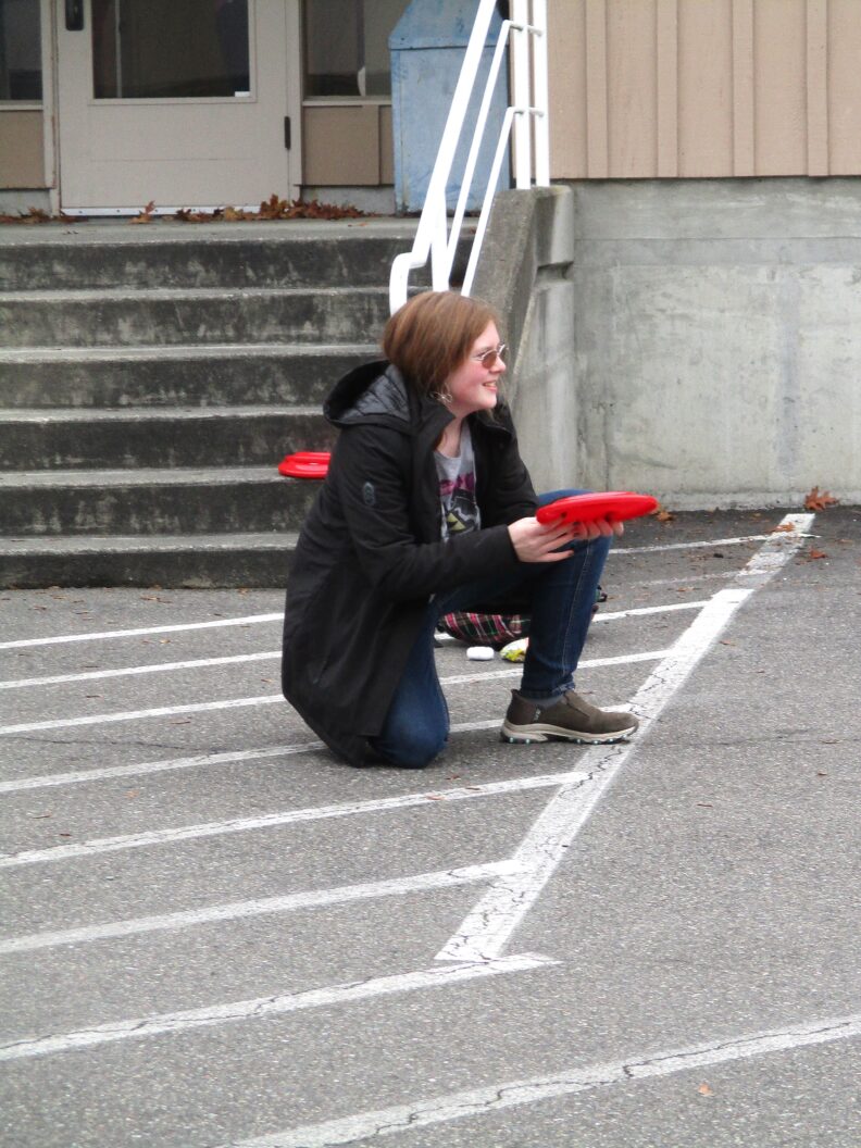 A youth member playing a frisbee game outside.
