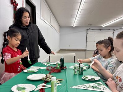 Youth members creating trees on paper by painting green with forks.