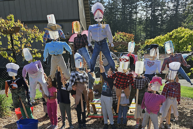 Kids holding scarecrows at Gig Harbor Demo Garden