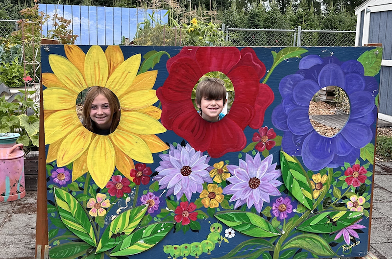 Kids with a photo op behind a flower wall