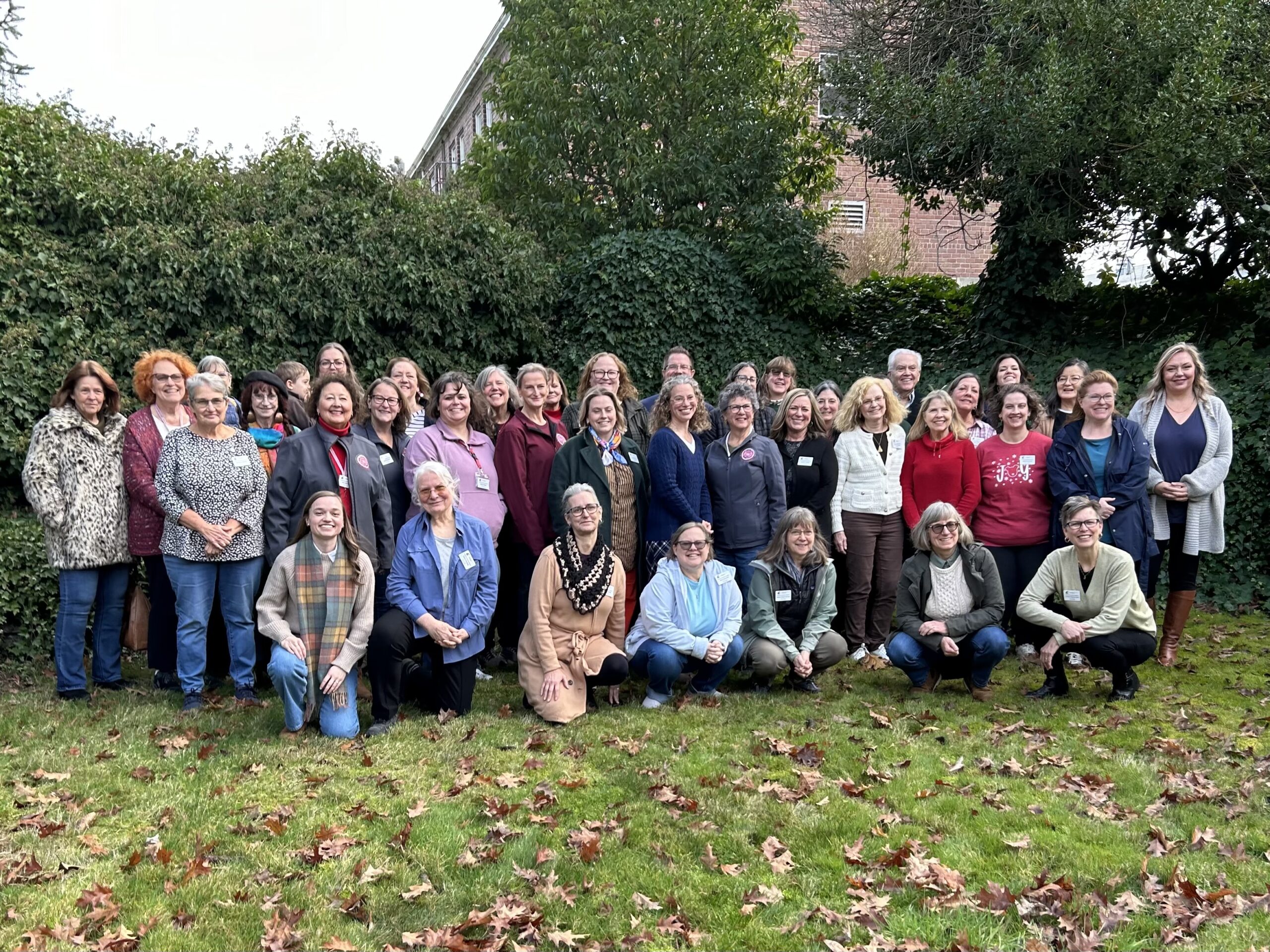 Group of people posing in two rows in front of trees.
