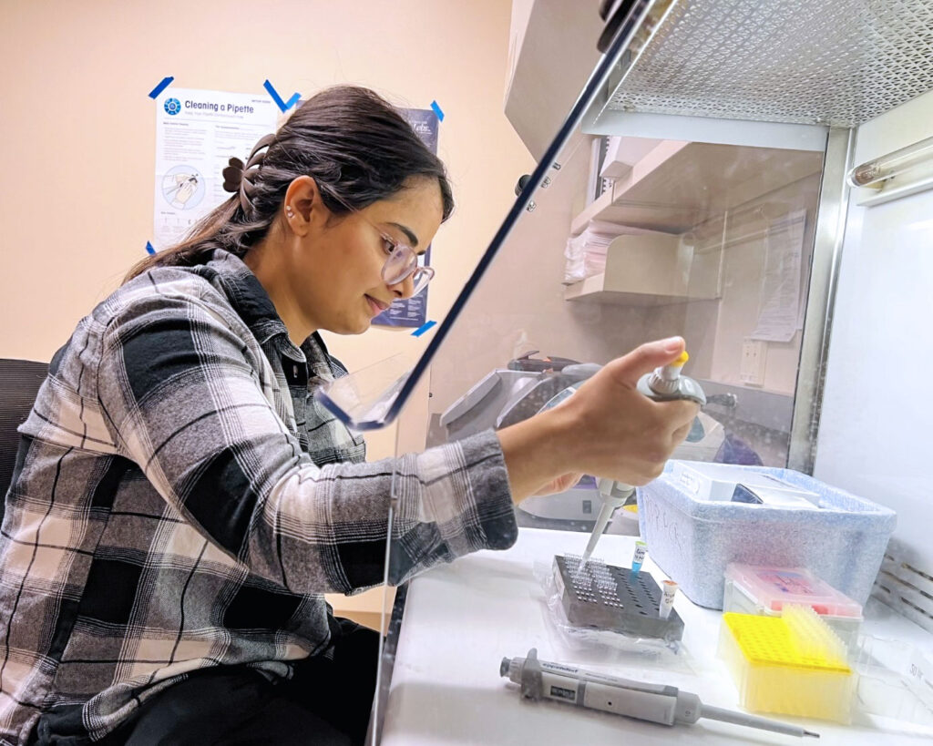 Woman using a pipette to transfer samples in a laboratory.