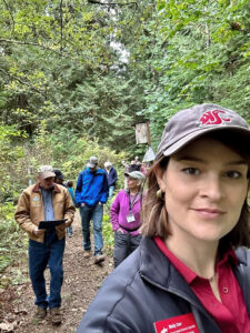 Woman taking selfie on a wooded trail.