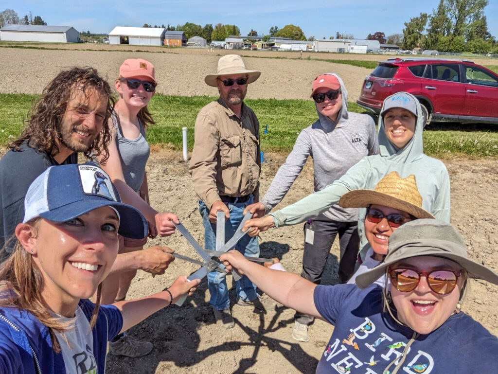Eight people standing in…e holding metal stakes.