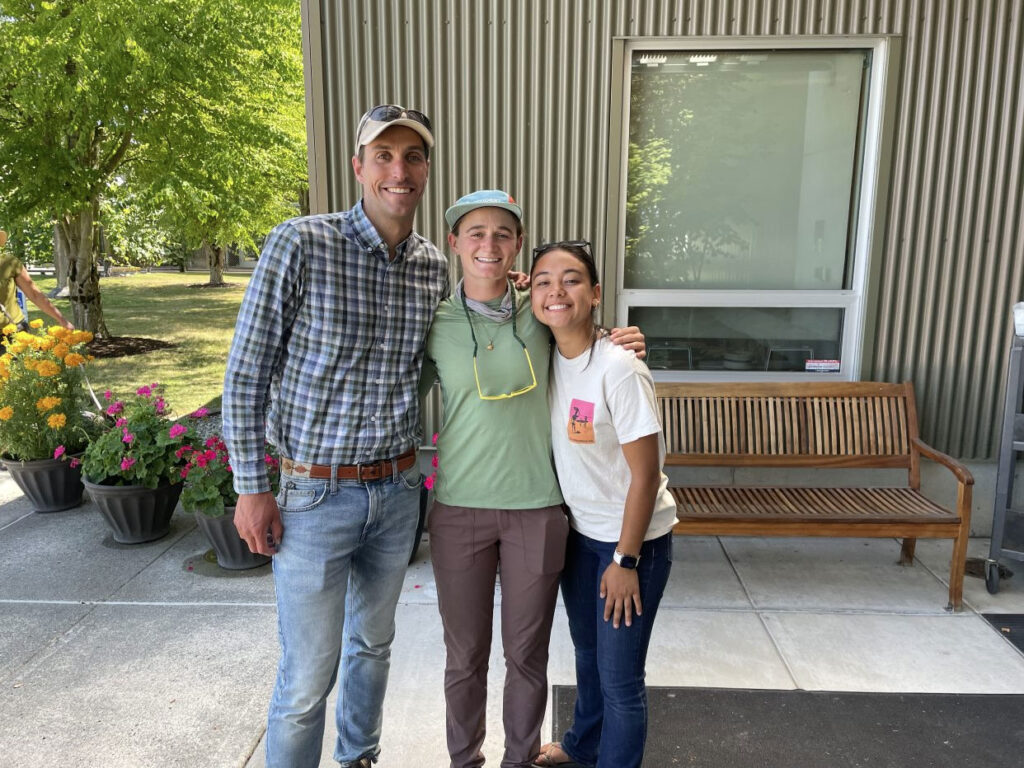 Man and two women pose in front of a building.