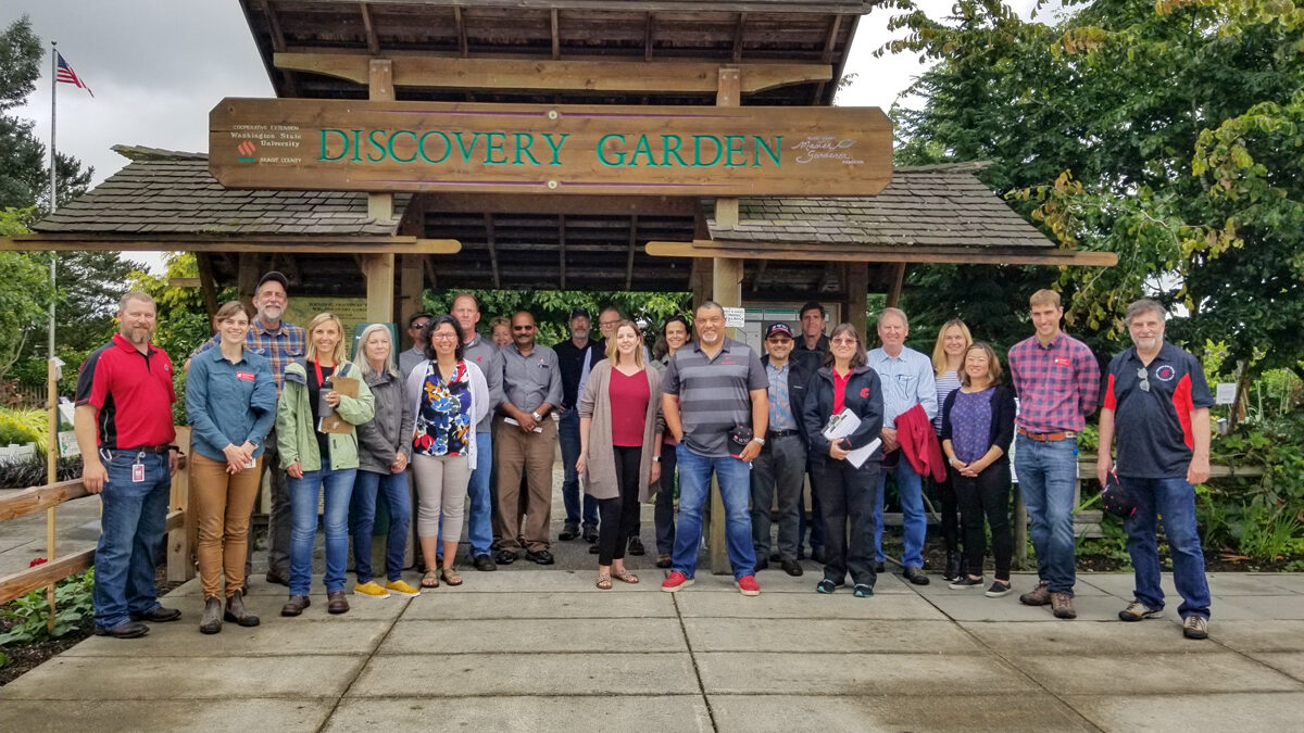 Large group stands at the entrance to the NWREC Discovery Garden.