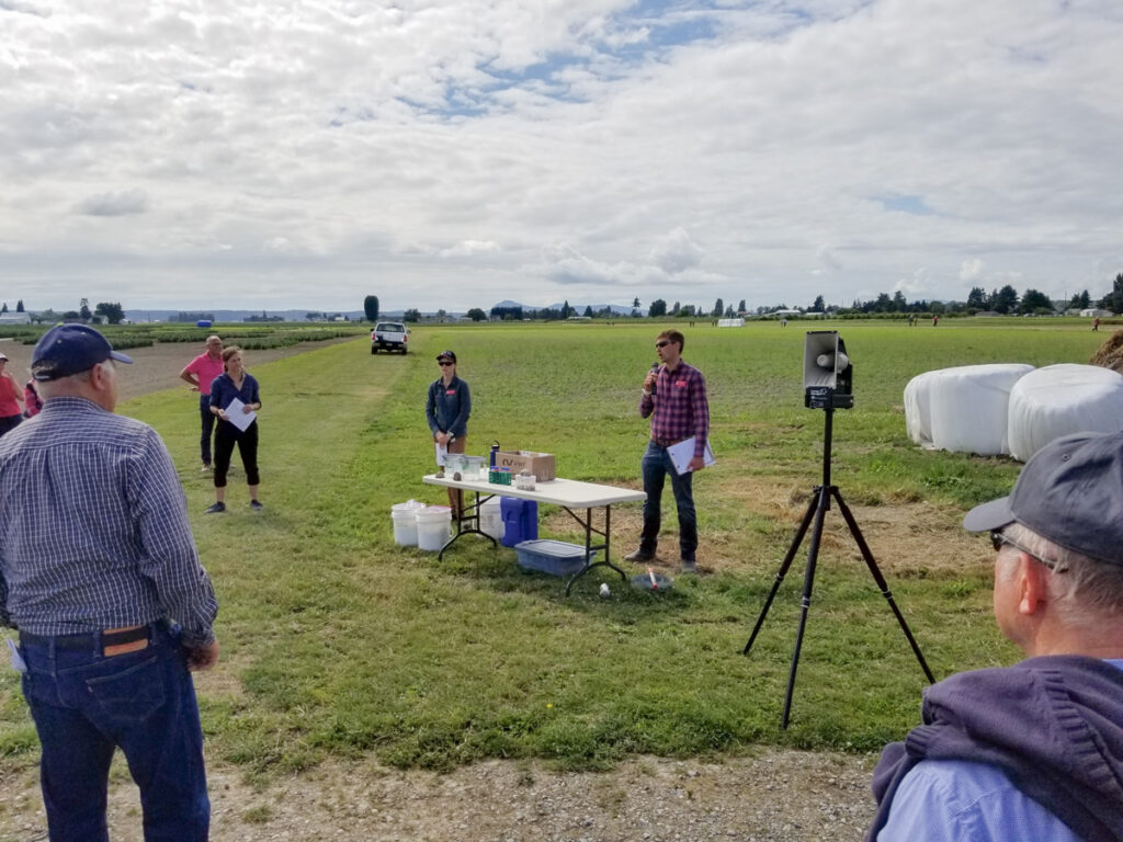 Man uses a microphone to speak in a field.