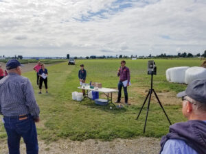 Man uses a microphone to speak in a field.