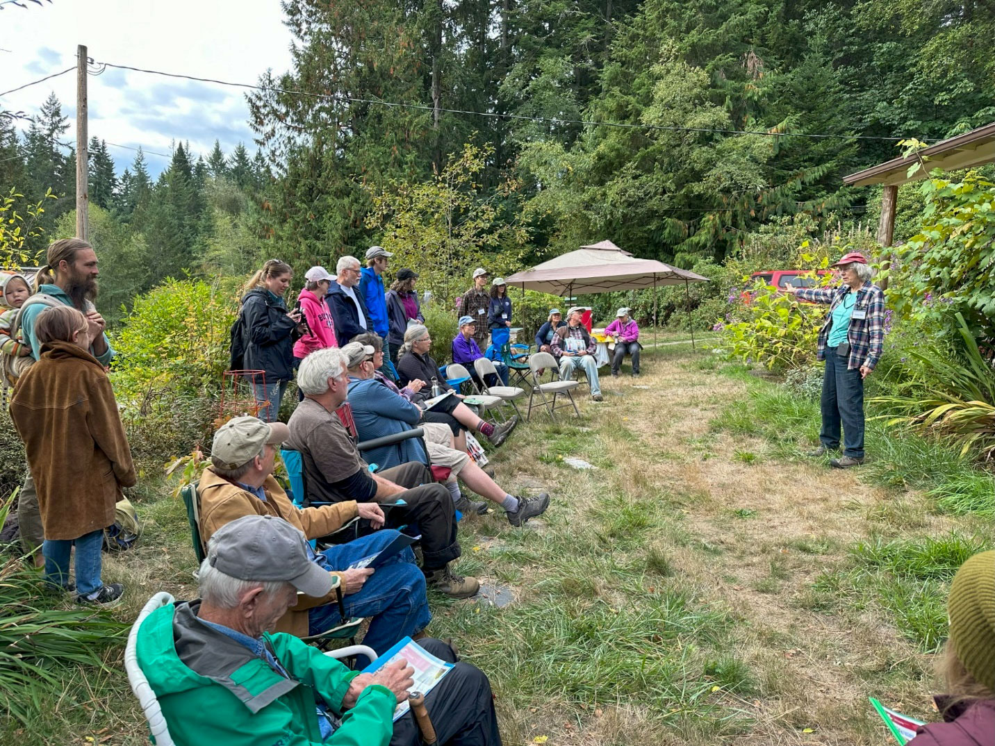 People seated listening to a presentation outdoors.