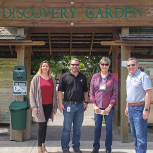 Four people stand in front of entry to the NWREC Discovery Garden.