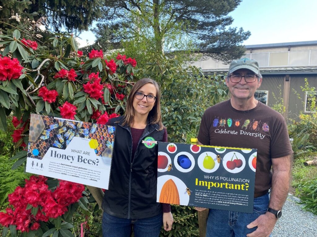 Woman and man holding signs in a garden.