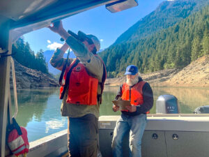 Two men on a boat. Man in forground using binoculars.