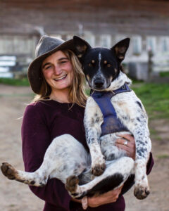 Woman in a hat holding a dog.