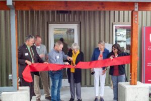Six people cutting ribbon to dedicate a building.