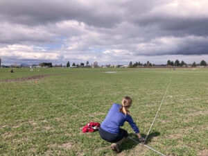 Woman in field measures plot boundaries.
