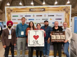 7 people pose with soil-related signs