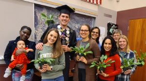 Group of people holding potted plants.