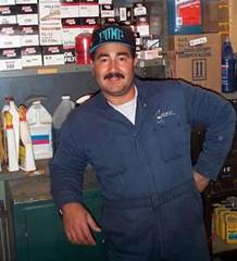 Man in coverall leans on a workbench.
