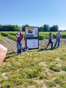 Huan Zhang presenting with a megaphone in a field.