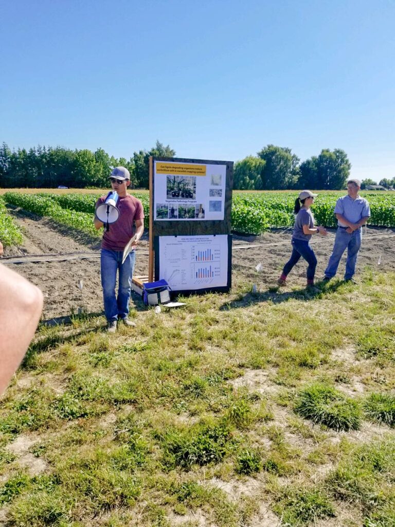 Huan Zhang presenting with a megaphone in a field.
