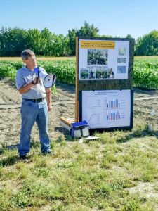 Mike Derie presenting with a megaphone in a field.