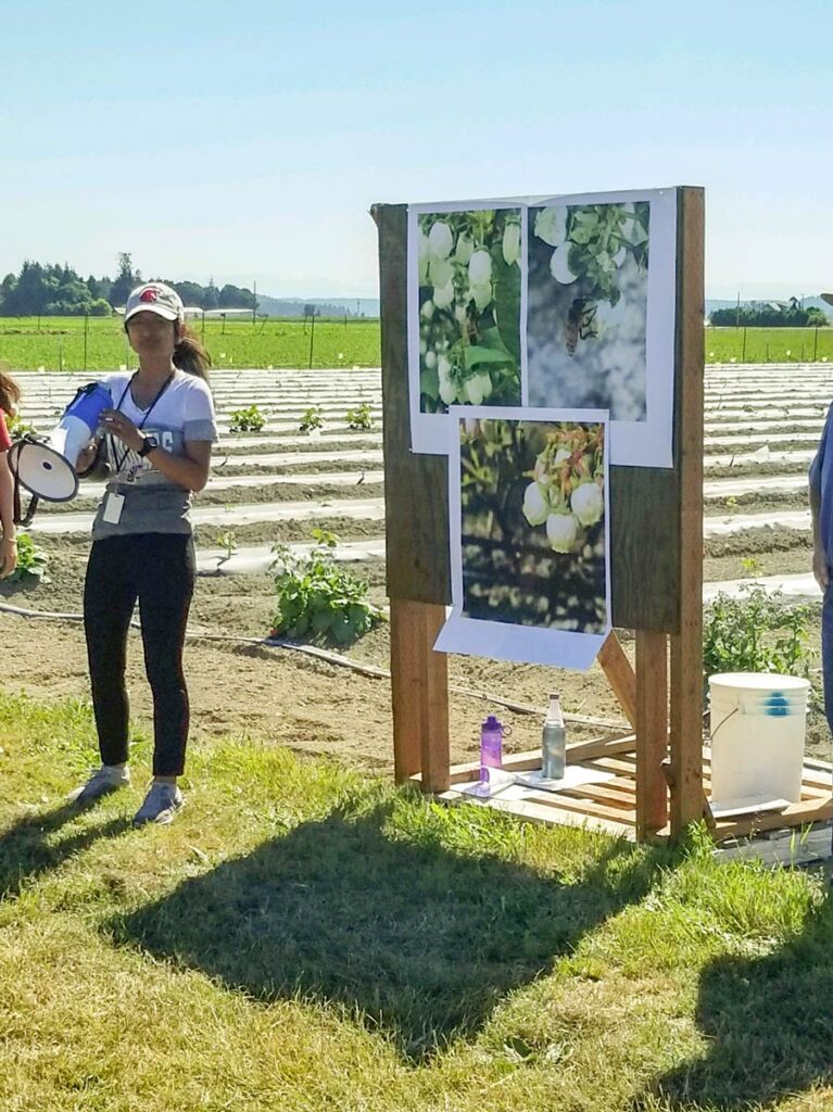 Pinki Devi presenting with a megaphone in a field.