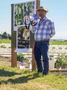 Sanjaya Gyawali presenting with a megaphone in a field.