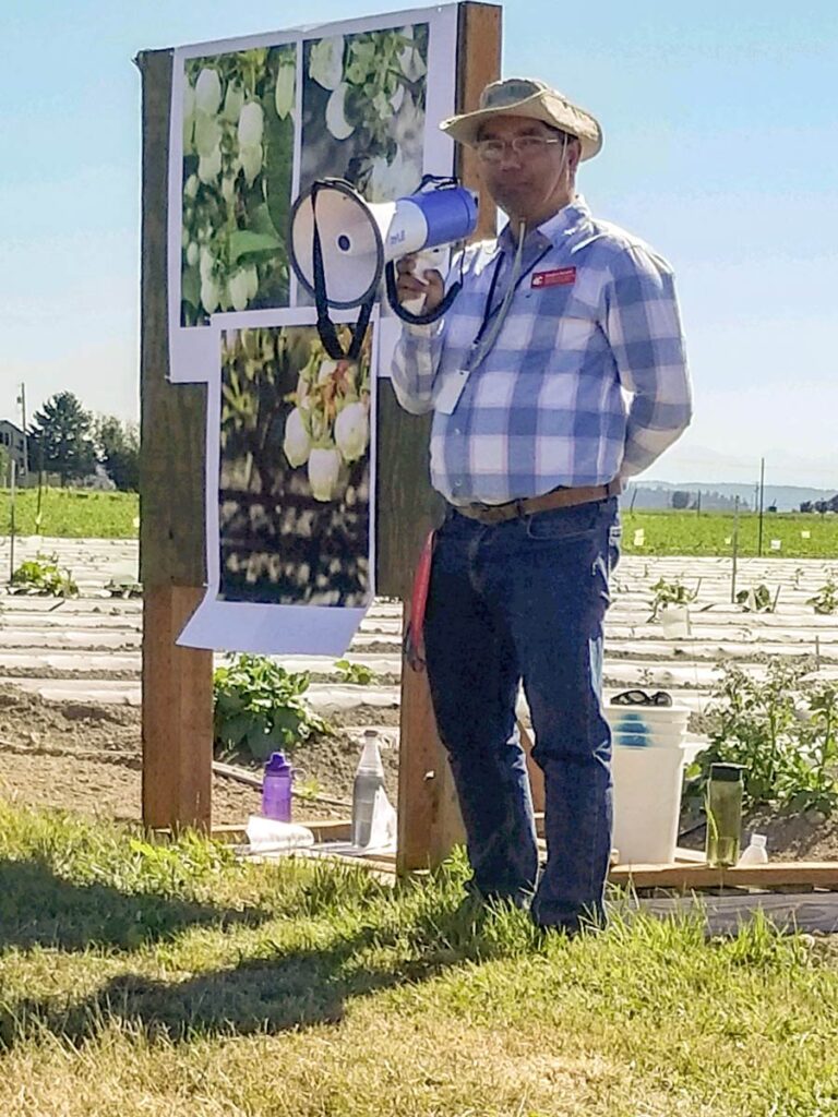 Sanjaya Gyawali presenting with a megaphone in a field.