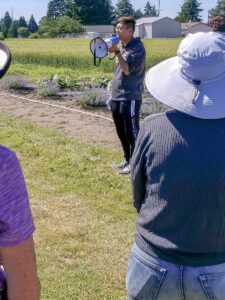 Yao Mu presenting with a megaphone in a field.
