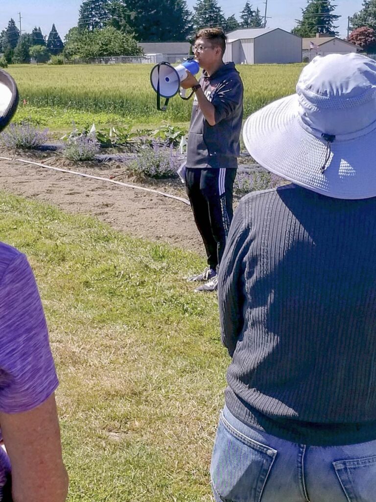 Yao Mu presenting with a megaphone in a field.