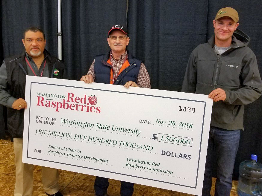Three men holding an oversized check for $1.5 million from the Washington Red Raspberry Commission.