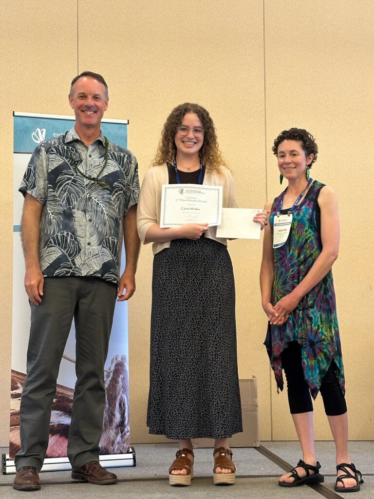 A woman receiving an award from a man and a woman.