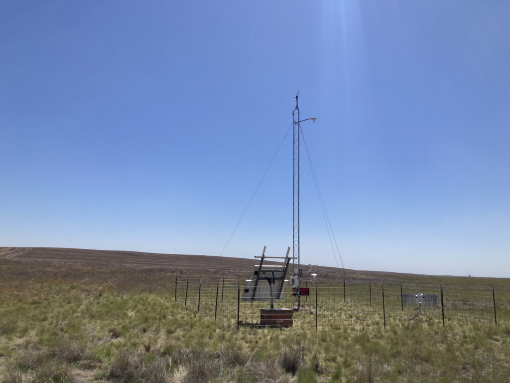 A tower supporting meteorology instruments surrounded by low brush.