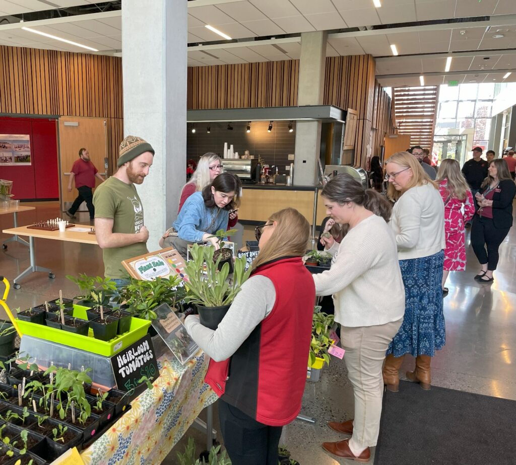 People looking at plants on a table.
