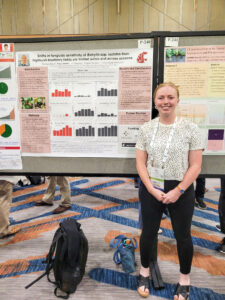 A woman standing in front of a peach colored poster presenting research methods and results.