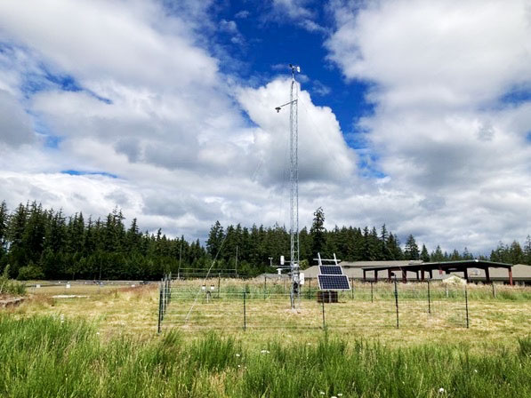 An antenna, sensors, and solar panels in a grassy field
