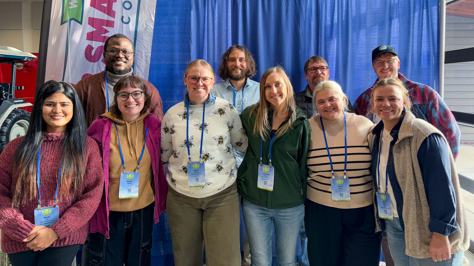 Ten people standing in front of a blue fabric drape.