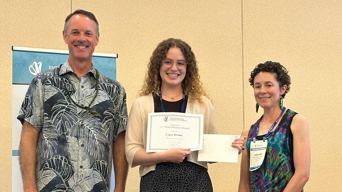 A woman receiving an award from a man and a woman.