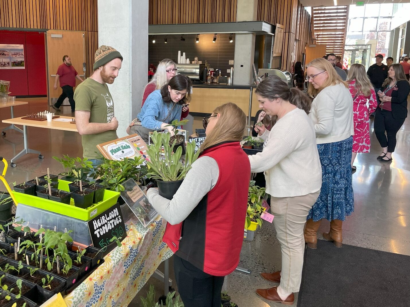 People looking at plants on a table.