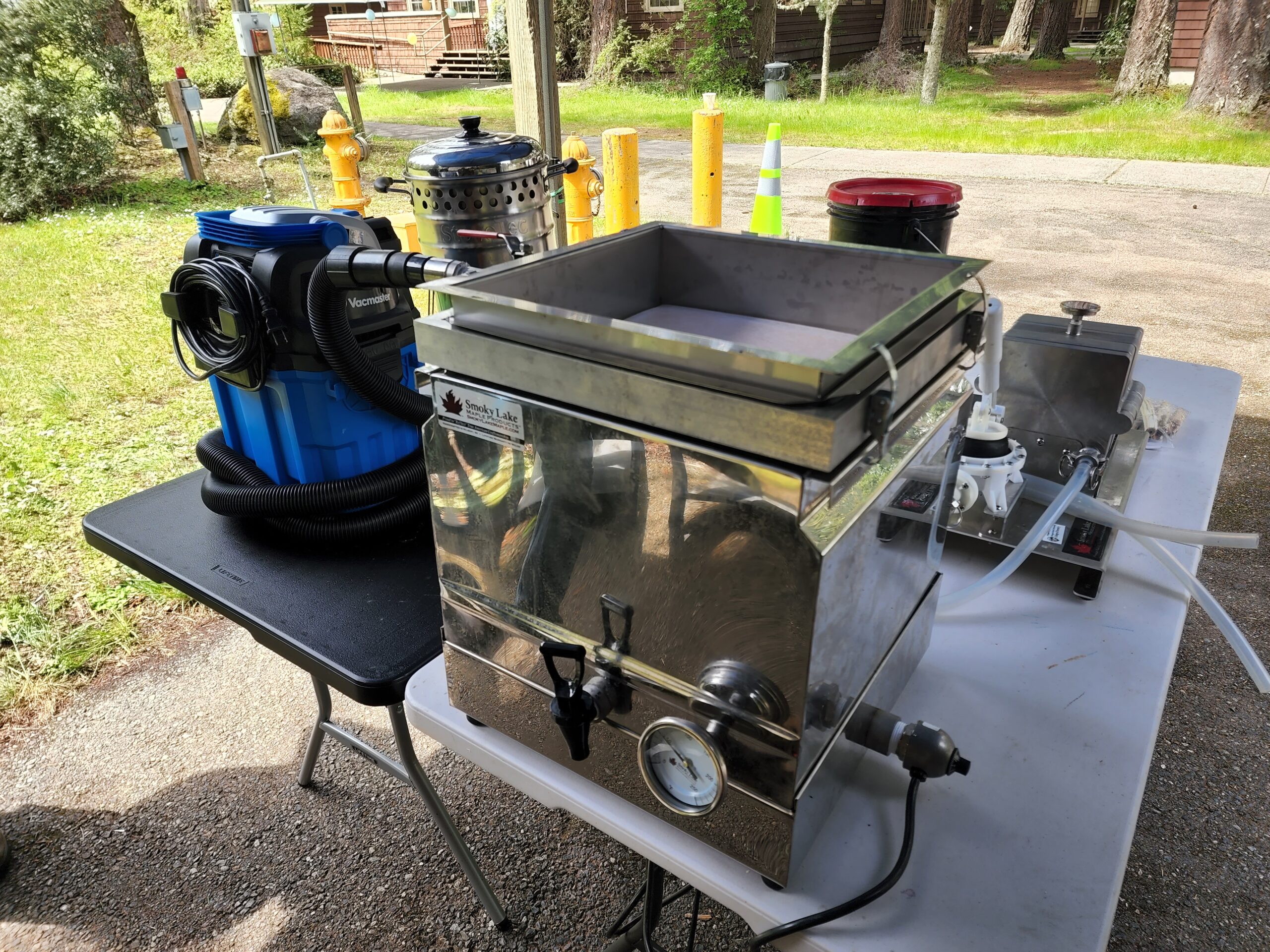 A stainless steel maple syrup filter attached to a shop vacuum.