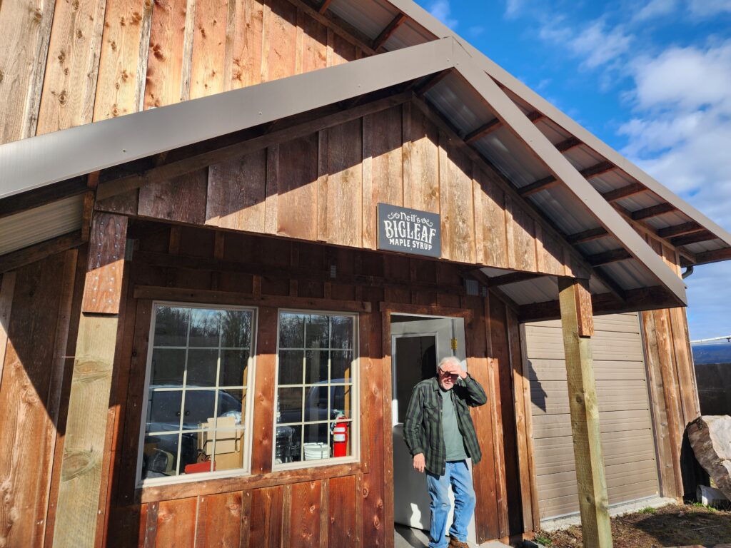 The entrance to Neil's Bigleaf Maple Syrup sugarshack with Neil standing out front.