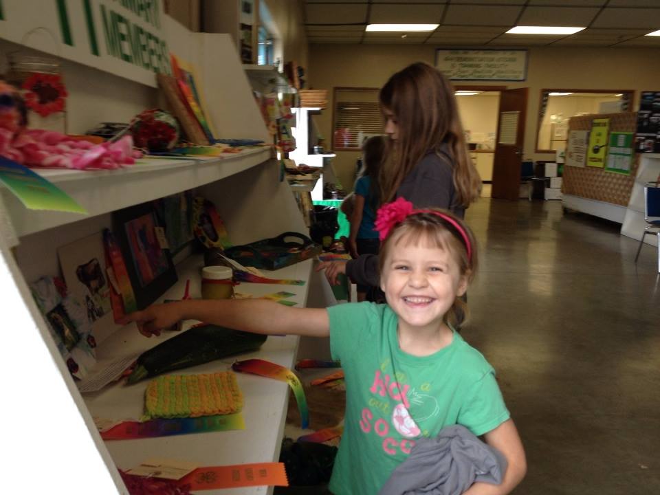 Female youth smiling while browsing shelves in a classroom. 