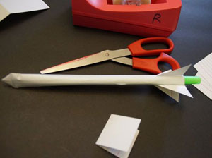 Scissors, paper, and straw on a table. 