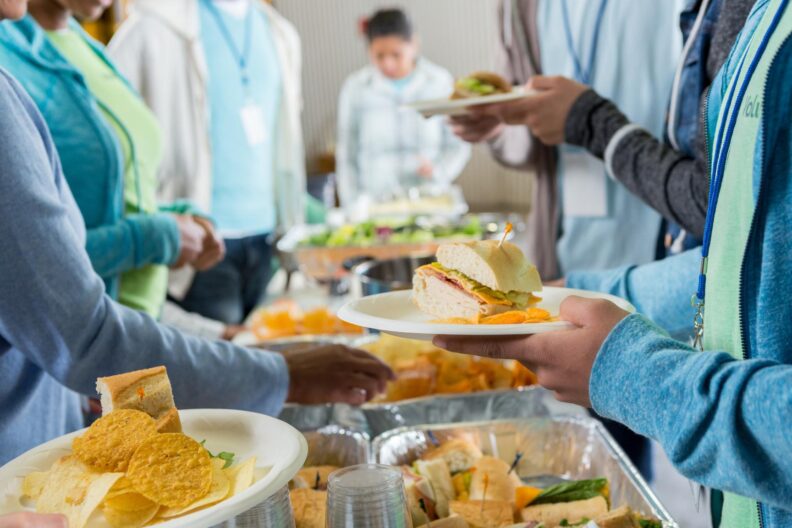 People giving and collecting food in a buffet line. 