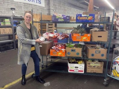 Food Waste Hero, Rachel Beason in front of food items on a rolling shelf. 
