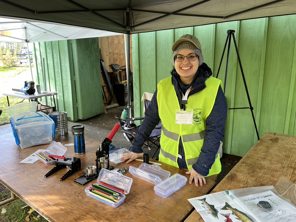 Photo of Kitsap Regional Library employee and Salmon Docent leading the button making station at Clear Creek Ridgetop Pavilion for Salmon Tours event