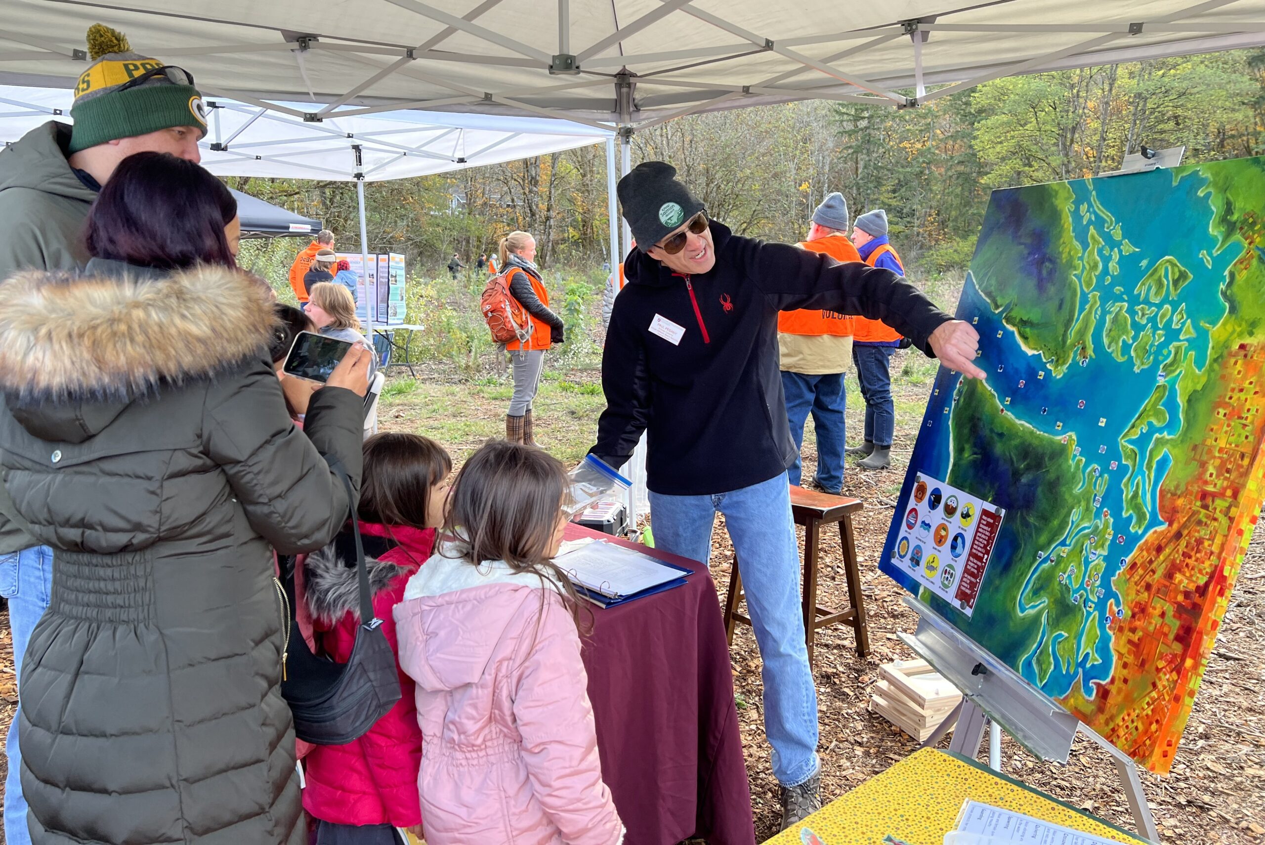 Photo of Salmon Docent teaching a family about the path of salmon through puget sound at Salmon Tours event